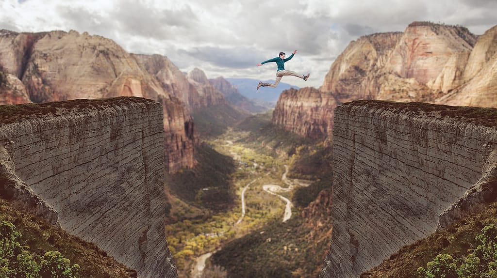 AI-generated image of a man leaping across a wide gap between two cliffs, symbolizing the impossible feat of overcoming challenges through self-belief.