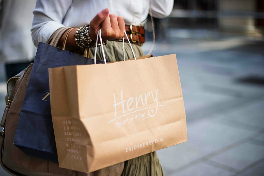 Female holding multiple shopping bags after a spree, symbolising short-term gratification and potential signs of an identity crisis.