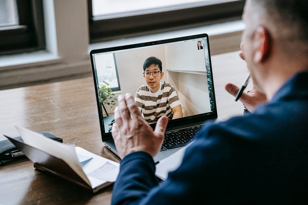 Man in a business suit mentoring a teenage boy over a laptop.