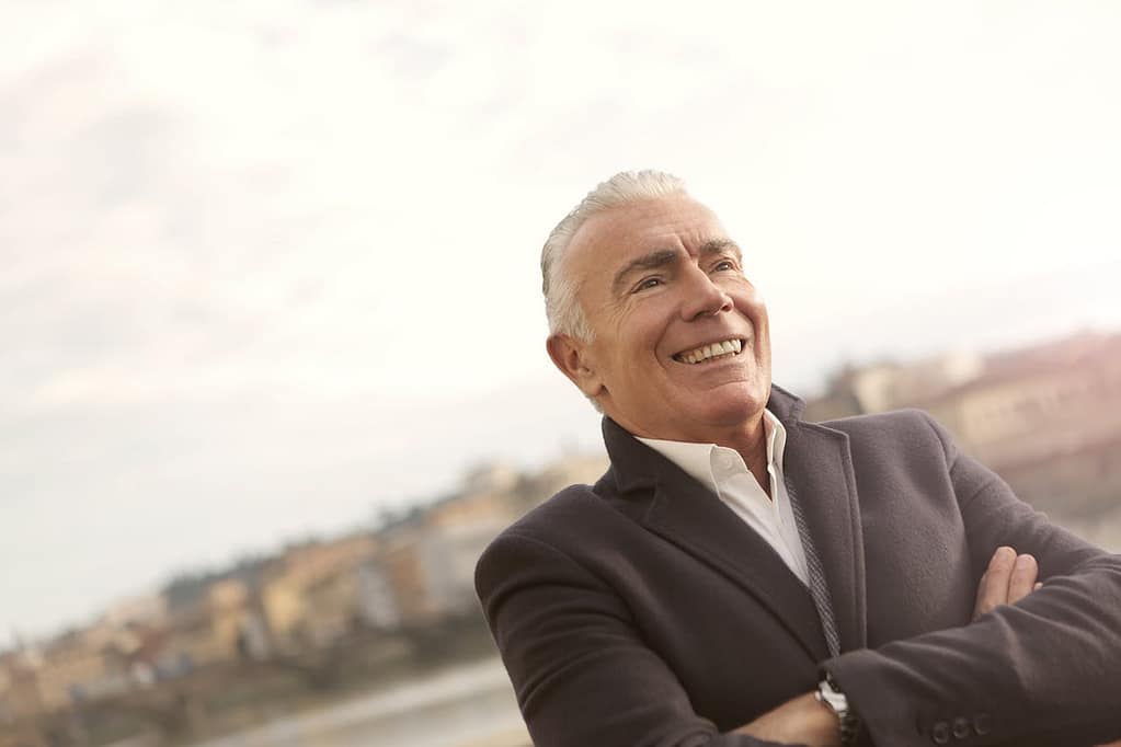Well-groomed man in a black suit jacket, smiling confidently, symbolising maturity and self-assurance in later adulthood.