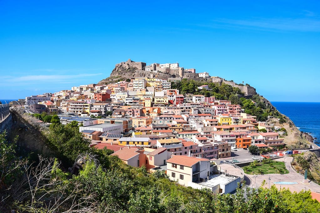 A view of Castelsardo, a historic town in Sardinia, Italy, with its iconic castle perched atop a hill, representing one of the Blue Zones known for its high percentage of centenarians.