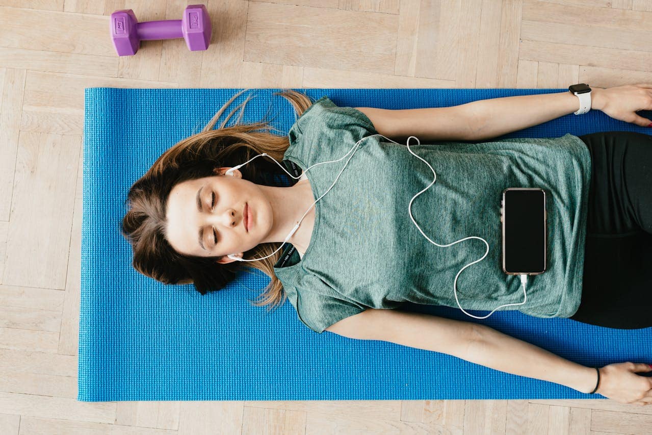 Woman relaxing on yoga mat while listening to healing sounds