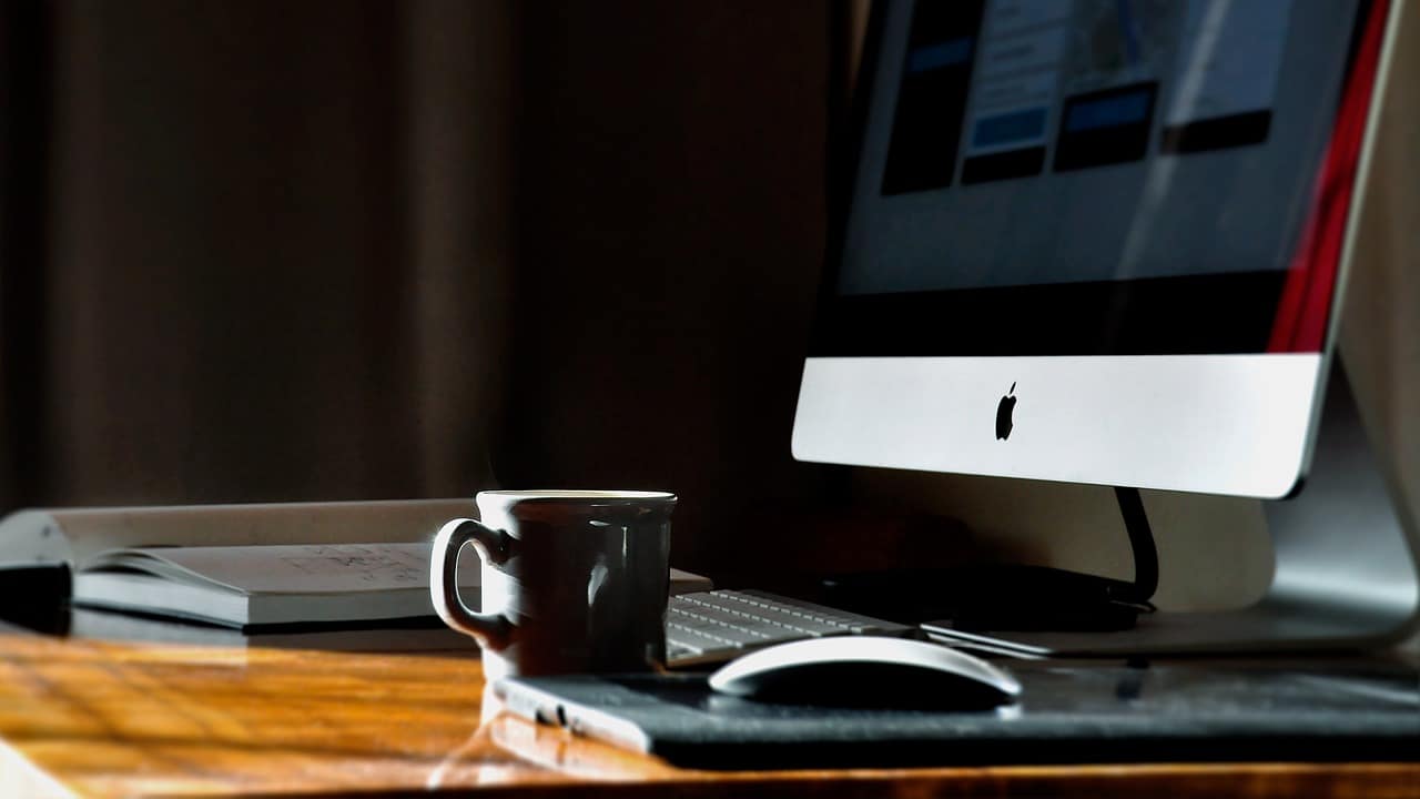 Organised desk with iMac, book, and mug - workspace for building discipline
