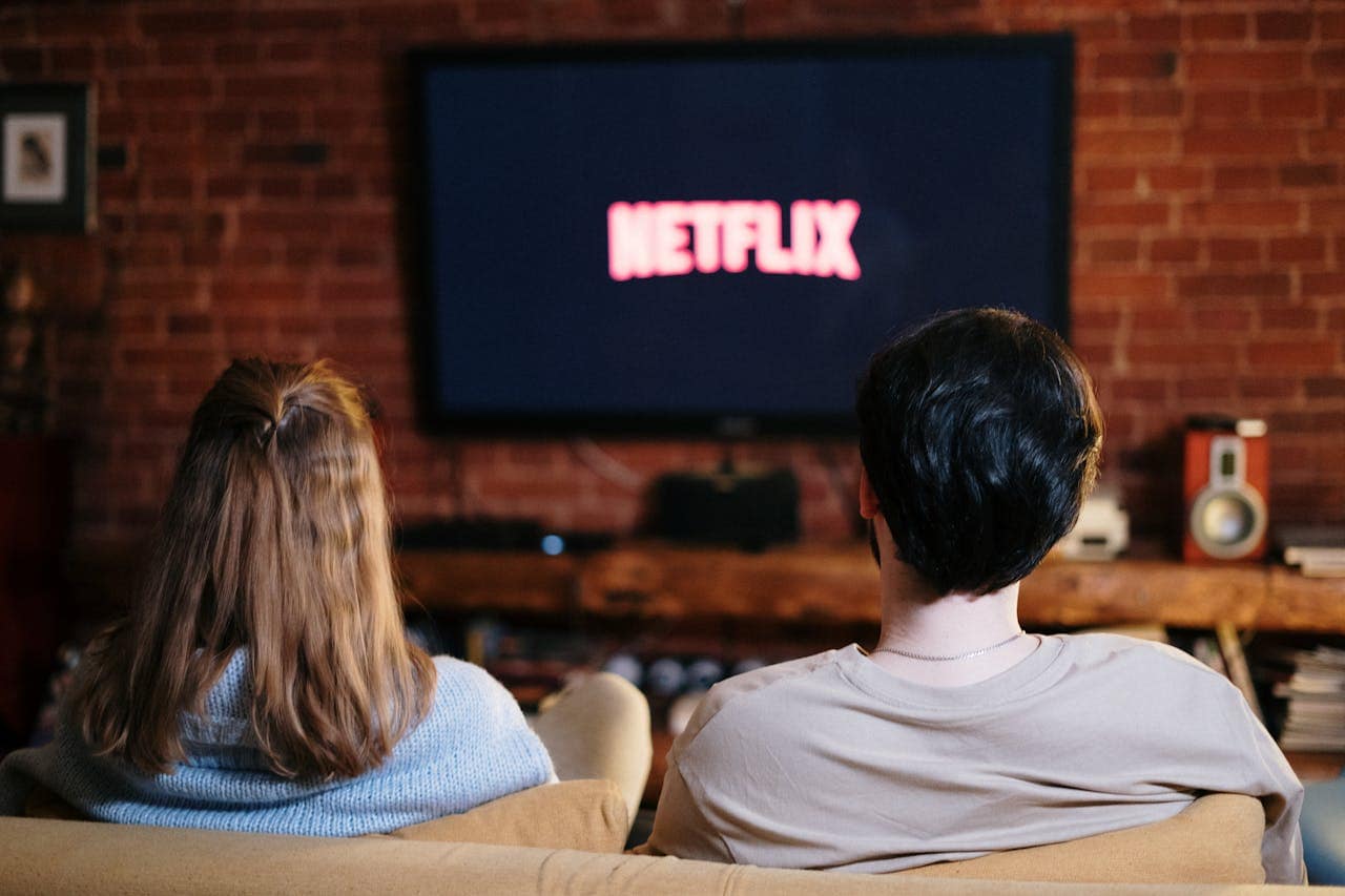 Couple binge-watching Netflix on couch, dopamine hijacking discipline habits