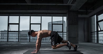 Fit man doing plank knee crunches in an empty industrial building under spotlight, symbolizing focus and discipline.