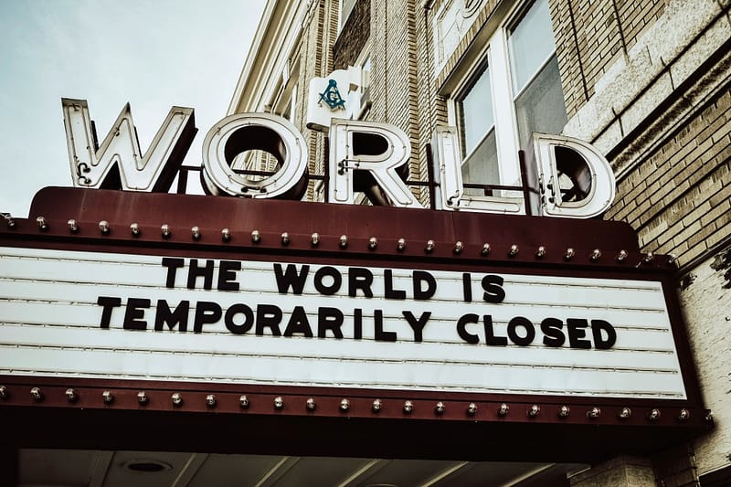 Empty theater with a sign reading 'The World is temporarily closed,' symbolizing the global impact of the COVID-19 lockdowns.