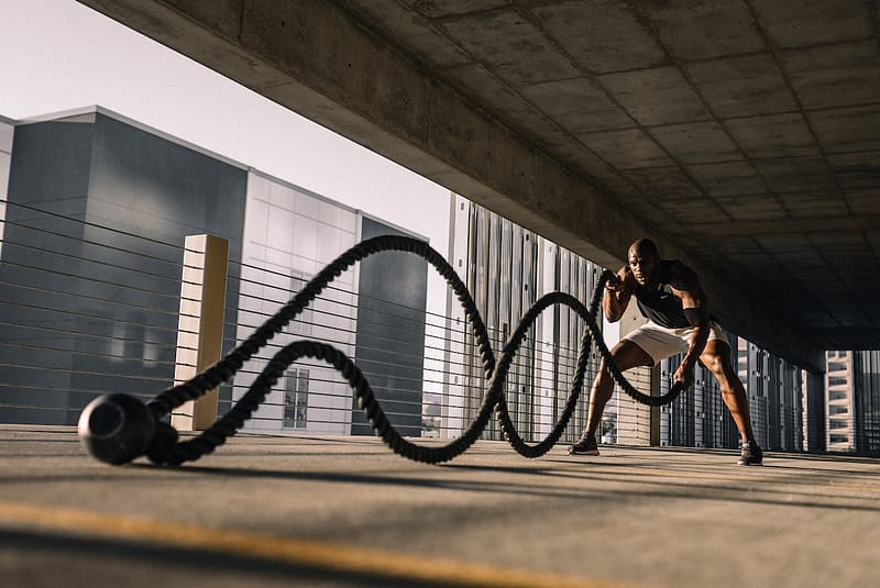 Fit man using battle ropes to demonstrate strength and metabolic flexibility.